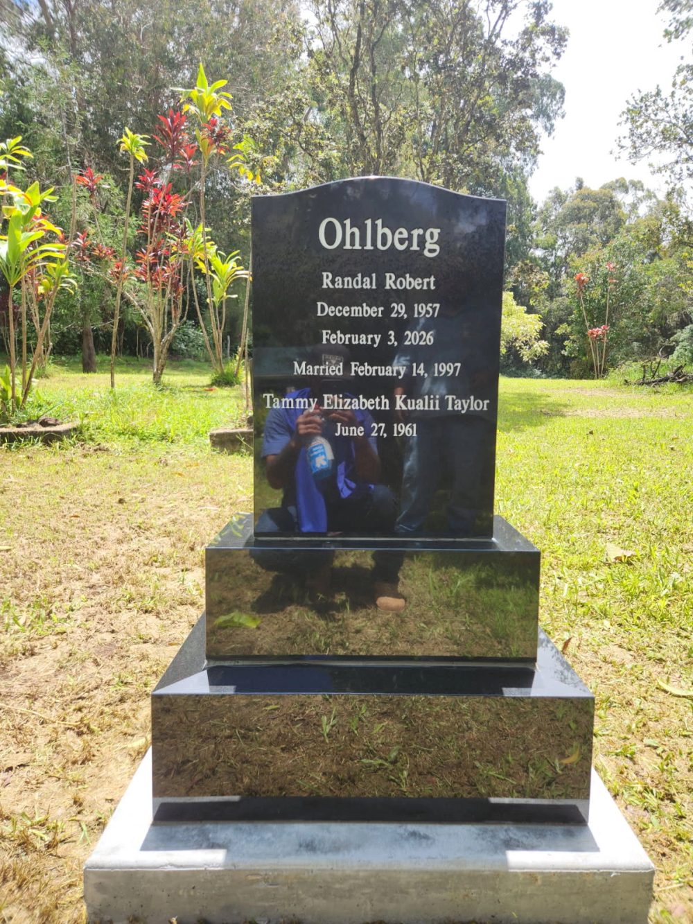 Black granite Ohlberg memorial with a portrait in a garden setting